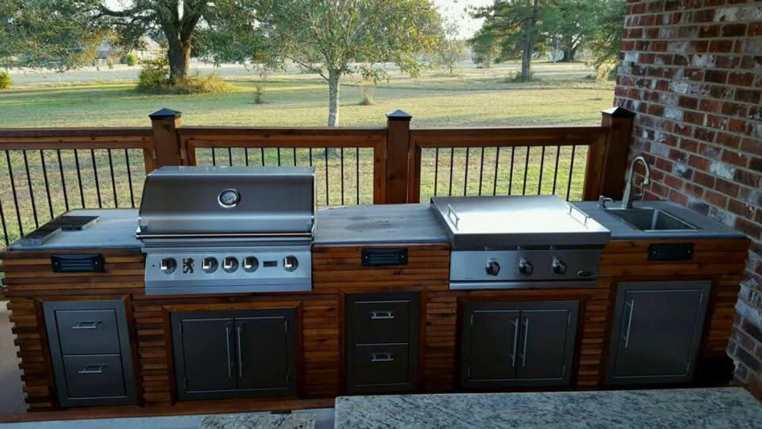 Outdoor kitchen with stainless steel grill, cabinets and sink